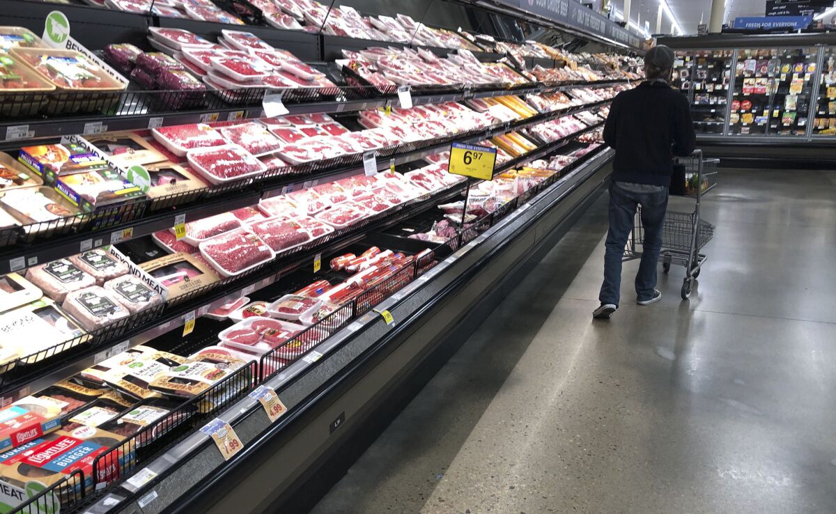 FILE - In this May 10, 2020 file photo, a shopper pushes his cart past a display of packaged meat in a grocery store in southeast Denver. Prices at the wholesale level fell from June to July, the first month-to-month drop in more than two years and a sign that some of the U.S. economy's inflationary pressures cooled last month. Thursday’s report from the Labor Department showed that the producer price index — which measures inflation before it reaches consumers — declined 0.5% in July. (AP Photo/David Zalubowski, File)