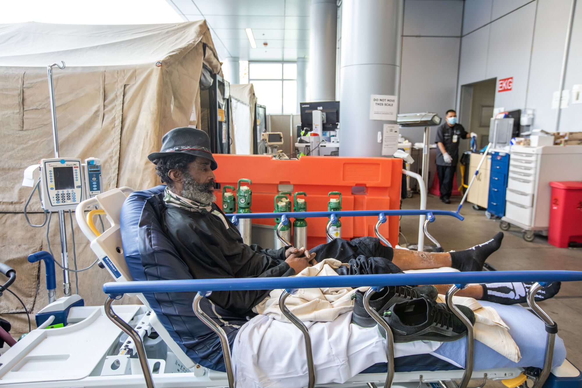 A man in a hat is lying on a hospital bed