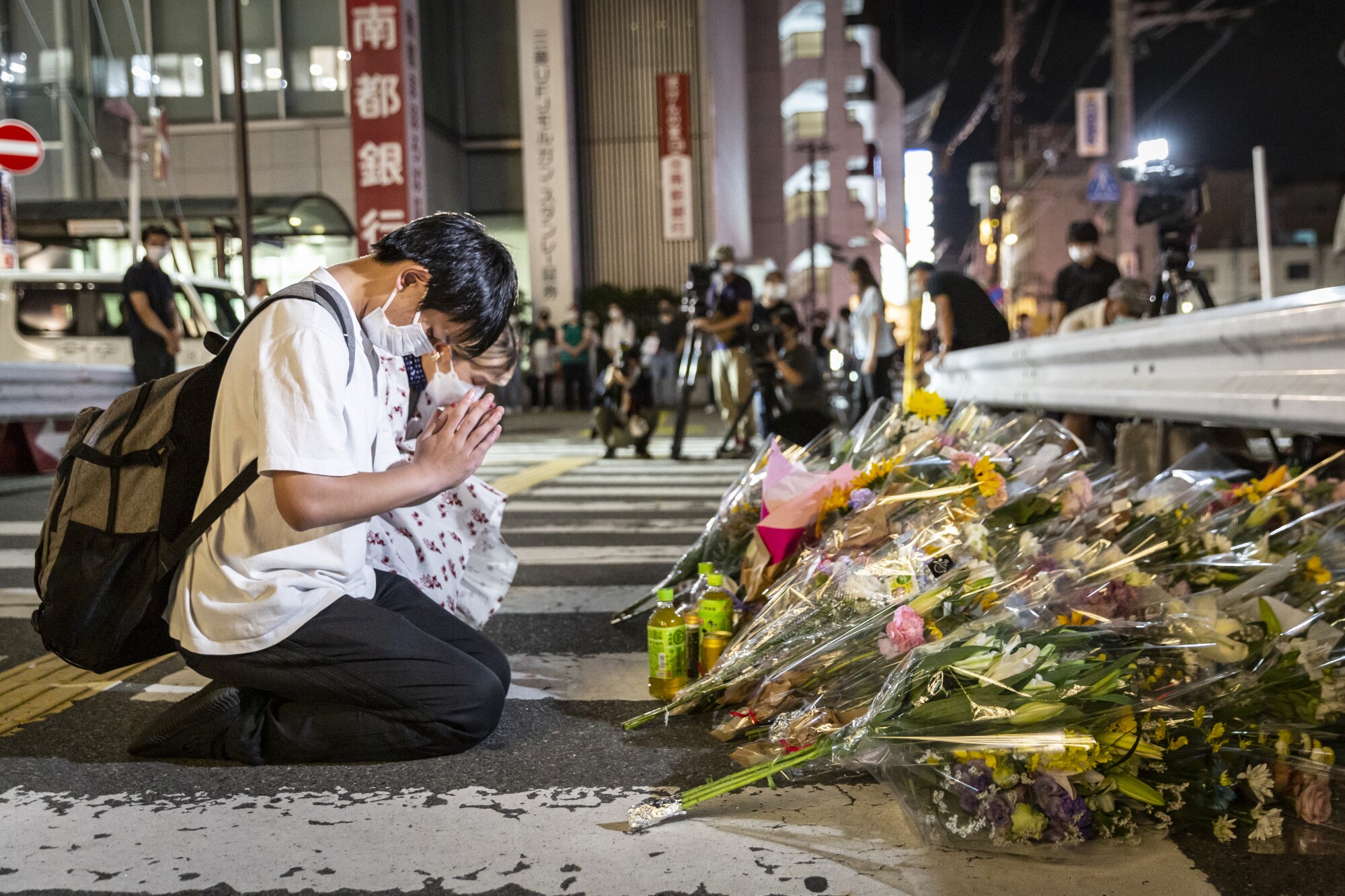 People pray at the site near the Yamato-Saidaiji station where former Japanese Prime Minister Shinzo Abe was shot dead.