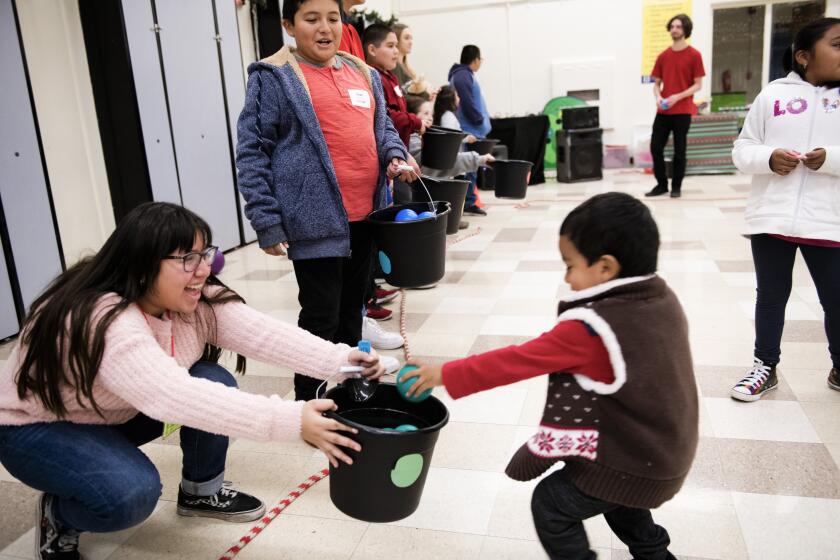 LENNOX CA DECEMBER 14, 2019 -- A boy collects balls as part of a game. While parents pick out gifts, the kids get to hang out in a playroom with other kids. Lennox Middle School hosts St. Margaret’s Center’s 31st Annual Christmas Program for 500 prescreened families living at or below the poverty level. More than 400 volunteers provided a day of Christmas activities for families in need. (Klaudia Lech / For The Times)