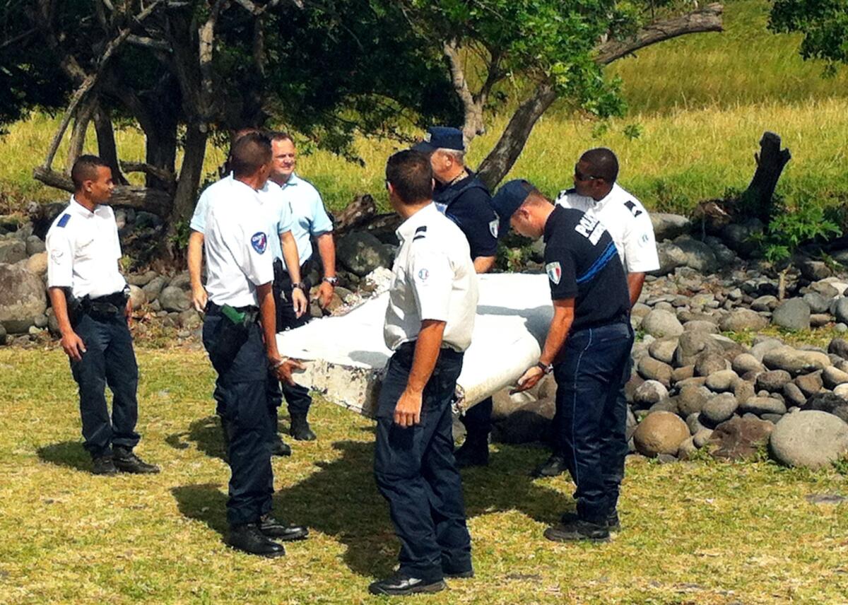 Police carry a piece of aircraft debris in the coastal area of Saint-Andre de la Reunion, a town on Reunion Island.