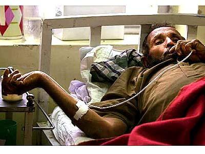 From a hospital bed in Quetta, Mohammad Aman, 60, drinks morning tea through a catheter tube.