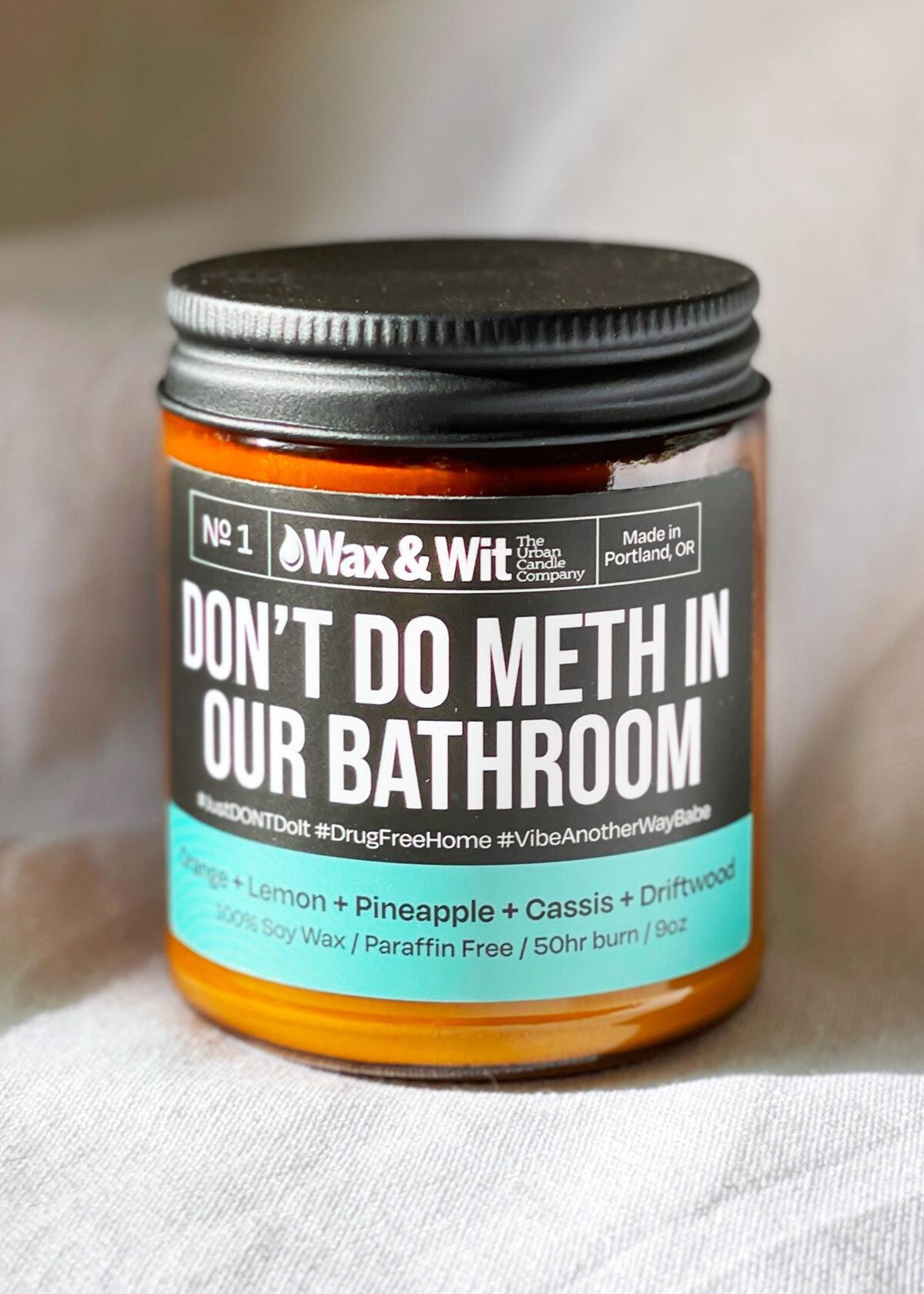 A candle in an amber screw-top jar with a label that reads "Don't do meth in our bathroom."
