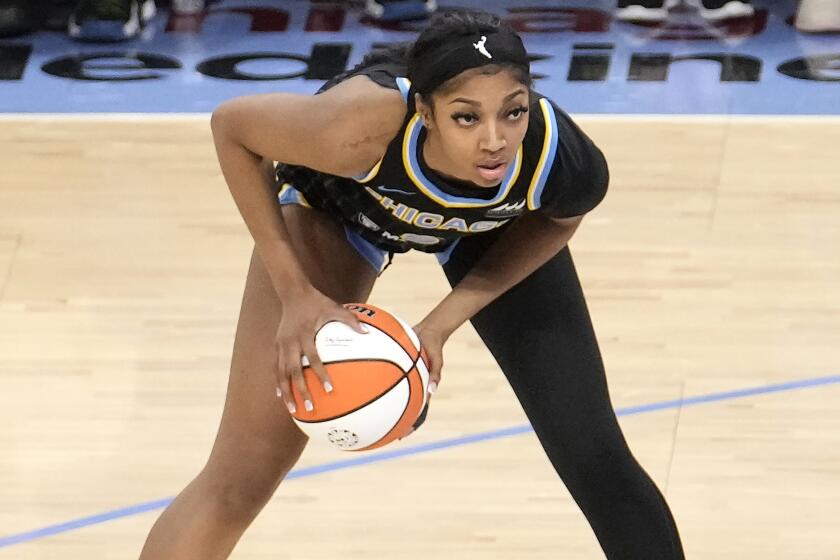 Chicago Sky's Angel Reese bends forward while looking to pass the ball. She's wearing a black sleeve on her left leg.