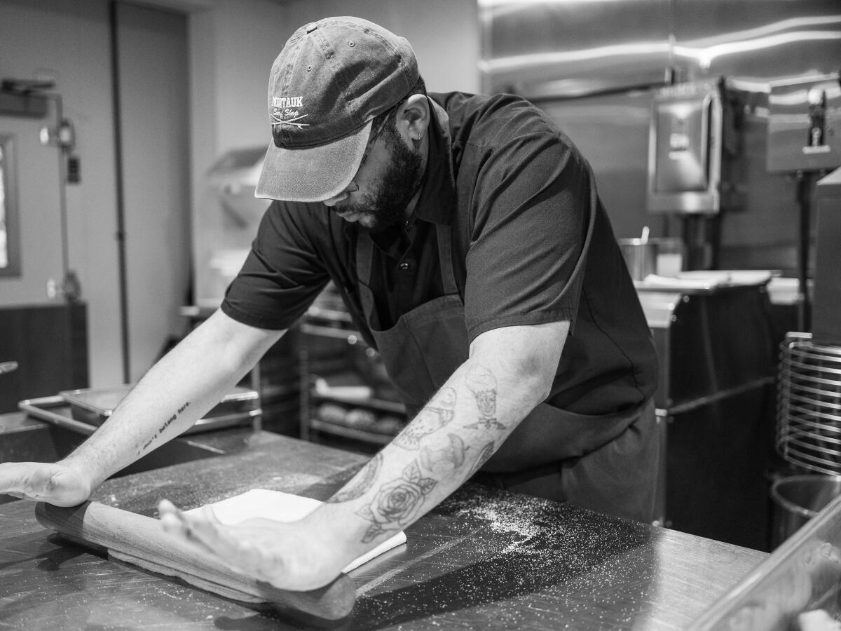 Pastry chef Joshua Ulmer rolling out dough in a restaurant kitchen