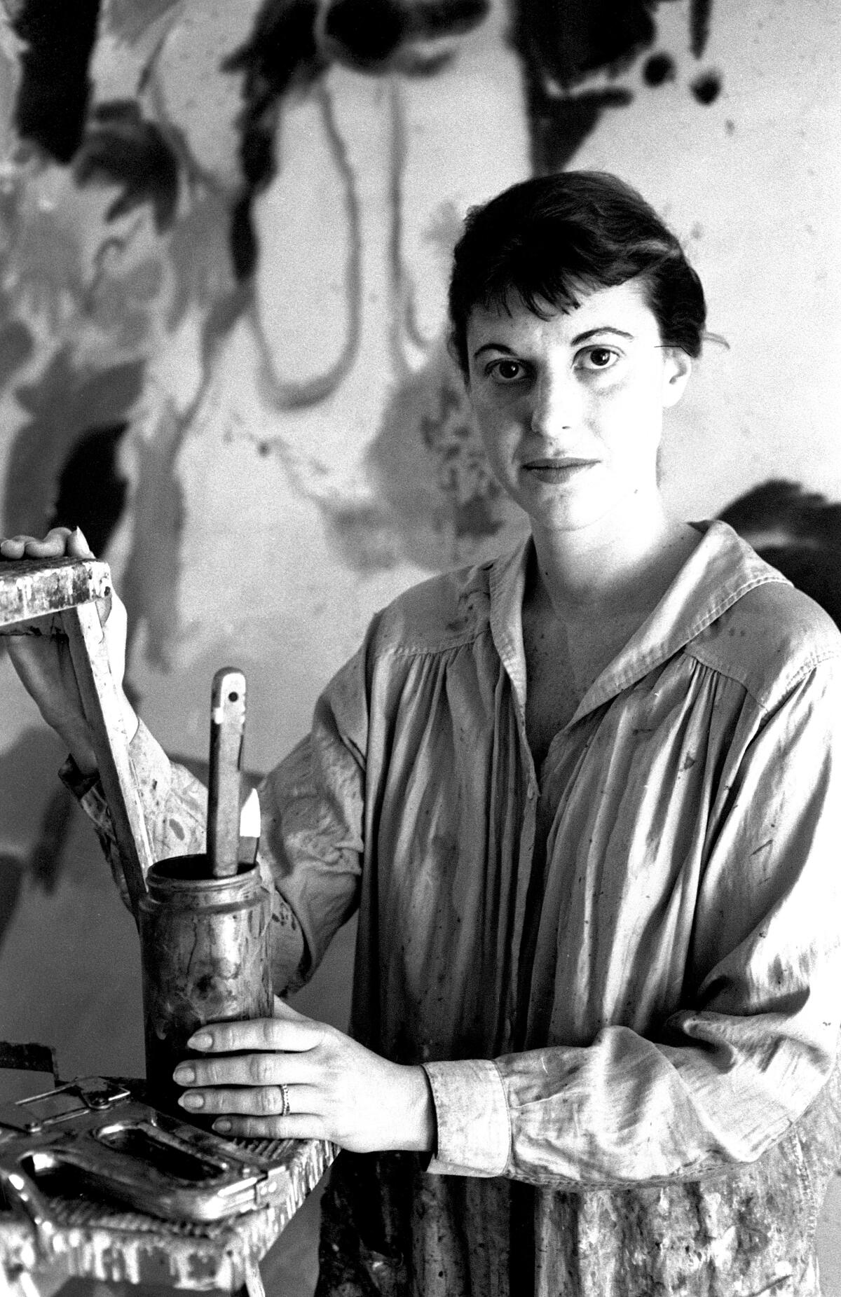 Helen Frankenthaler, Abstract Expressionist painter, in a smock and holding a paint bottle.