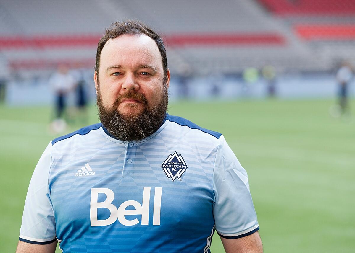 Actor Chris Gauthier poses for a photo in a blue soccer jersey on a soccer field