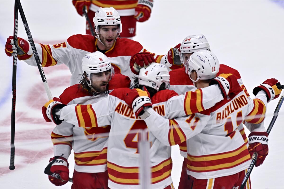 Flames defenseman Rasmus Andersson (4) celebrates with teammates after scoring the winning overtime goal Dec. 23, 2022.