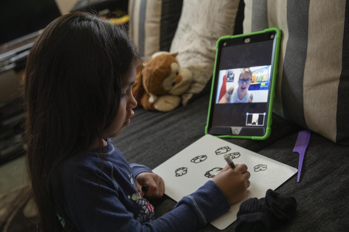 A girl talks to her teacher during a zoom class. 