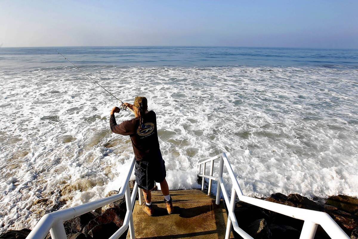 Joe Dombroski of Canoga Park fishes off public access stairs during high tide at Broad Beach in Malibu on March 24. Over several decades the beach has eroded significantly. To protect their properties, residents have piled sandbags and, more recently, built an emergency rock wall to hold back the tides.