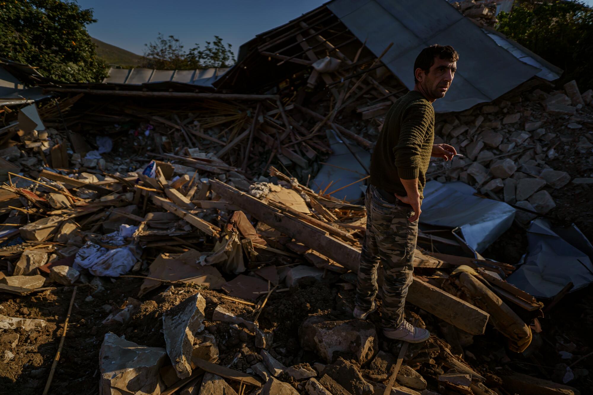 A man stands amid the ruins of a home after a military strike in Nagorno-Karabakh. 