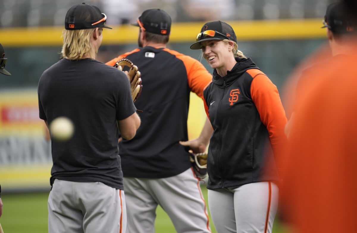 San Francisco Giants major league assistant coach Alyssa Nakken, right, chats with players as they warm up before a baseball game against the Colorado Rockies, Monday, May 16, 2022, in Denver. (AP Photo/David Zalubowski)