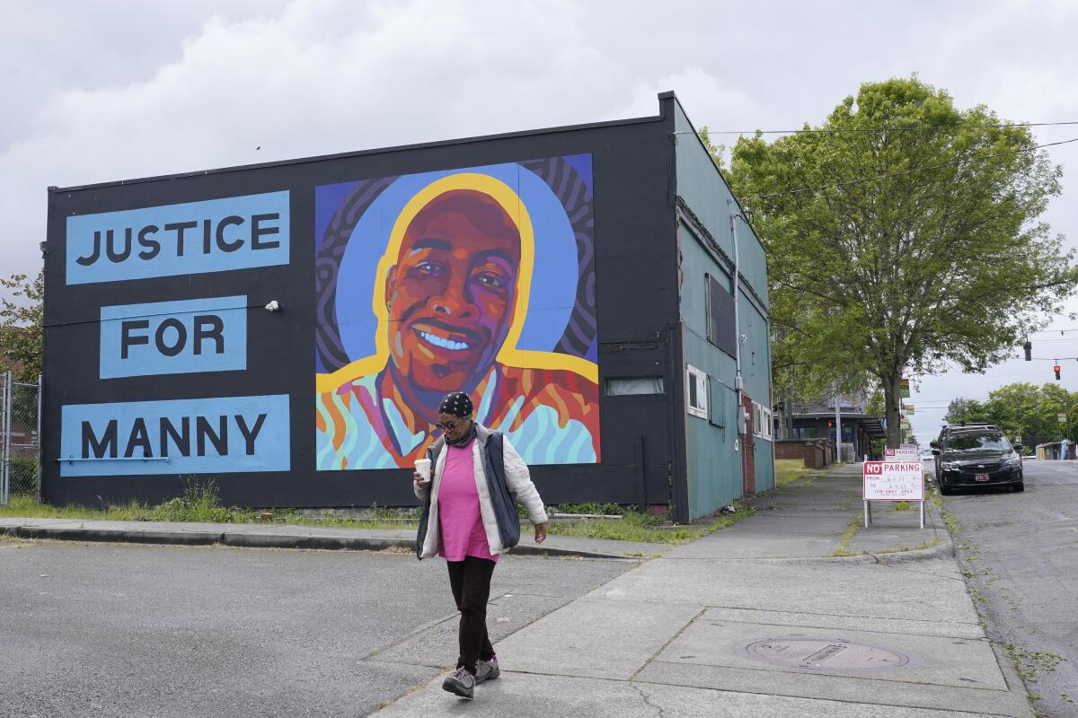 A woman walks past a mural honoring Manuel "Manny" Ellis, in the Hilltop neighborhood of Tacoma, Wash. 