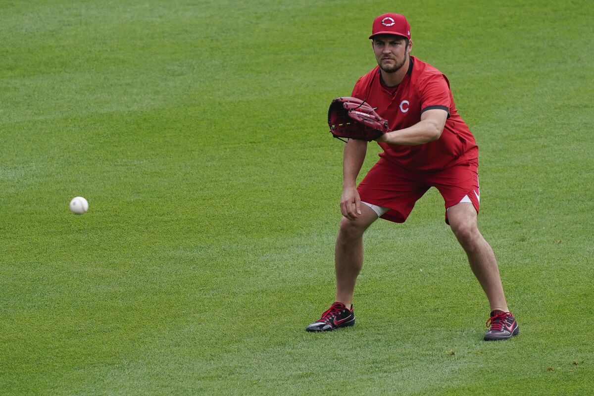Cincinnati Reds pitcher Trevor Bauer warms up in the outfield during team baseball practice at Great American Ball Park in Cincinnati, Wednesday, July 8, 2020. (AP Photo/Bryan Woolston)