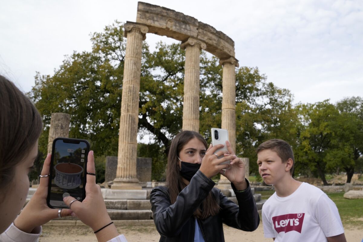 School students use a mobile app at the ancient site of Olympia, southwestern Greece, Wednesday, Nov. 10, 2021. Microsoft launched a digital restoration project at the ancient birthplace of the Olympic Games in southern Greece Wednesday to provide visitors an immersive recreation of temples and competition areas as they walk through the ruins. (AP Photo/Thanassis Stavrakis)