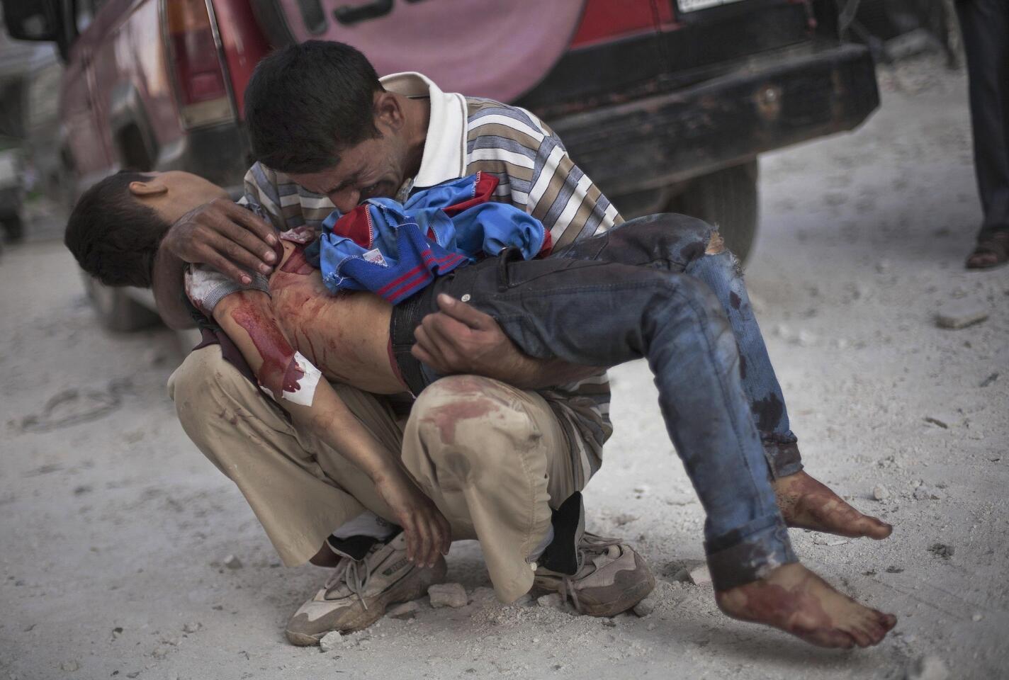 A Syrian man holds the body of his son, who was killed by government troops in Aleppo.