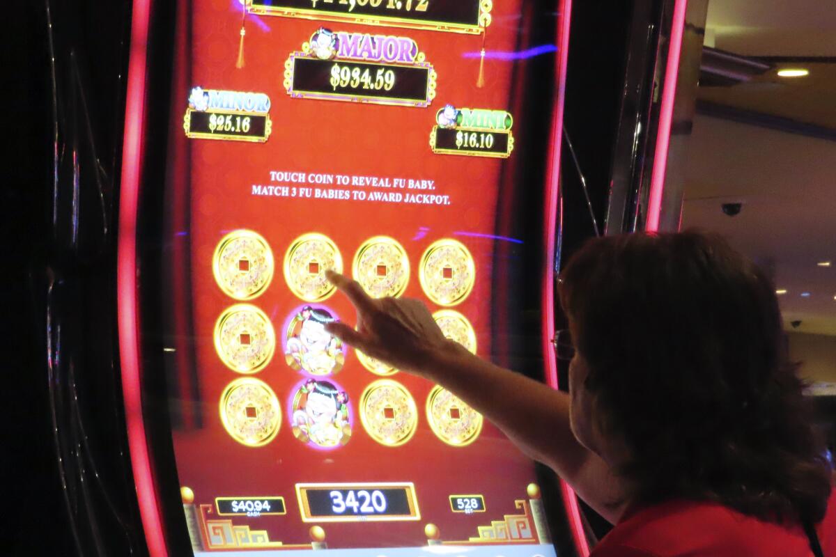 A gambler touches the screen of a slot machine at Harrah's casino in Atlantic City N.J., Sept. 29, 2023. Figures released, Tuesday, April 16, 2024, show Atlantic City's casinos, their online partners and horse tracks that take sports bets won over $526 million in March, a month in which New Jersey's internet gambling market set yet another monthly record at $197 million. (AP Photo/Wayne Parry)