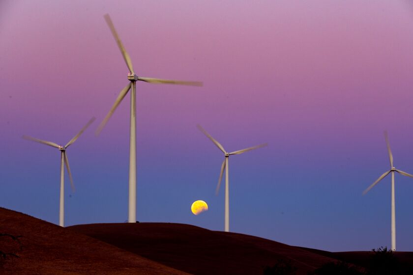 RIO VISTA, CALIF. -- WEDNESDAY, MAY 26, 2021: Turbines spin as the Blood Moon lunar eclipse sets behind the towers on the Shiloh II wind farm in the Montezuma Hills near Bird's Landing, Calif., on May 26, 2021. (Brian van der Brug / Los Angeles Times)