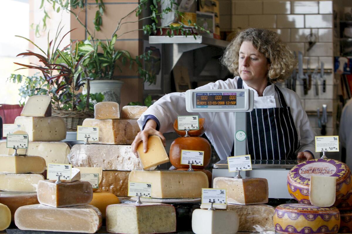 A woman picks up cheese at the Oxbow Public Market