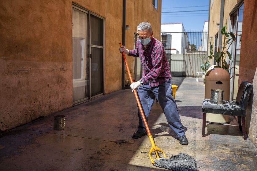 LOS ANGELES, CA - MAY 09: Armando Amaya mopping the outdoor courtyard at Villa Stanley on Monday, May 9, 2022 in Los Angeles, CA. Villa Stanley is an adult residential facility, also known as a board and care, which houses low-income individuals with serious mental illness who may not be able to live independently.(Francine Orr / Los Angeles Times)
