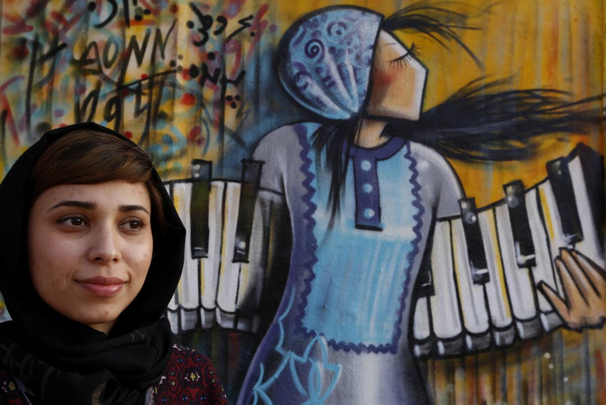 Shamsia Hassani stands in front of her mural in Los Angeles. The Afghan artist is in L.A. for a Hammer Museum residency.