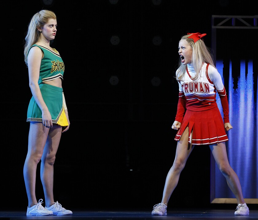 A cheerleader in a red uniform yells at a cheerleader in a green uniform