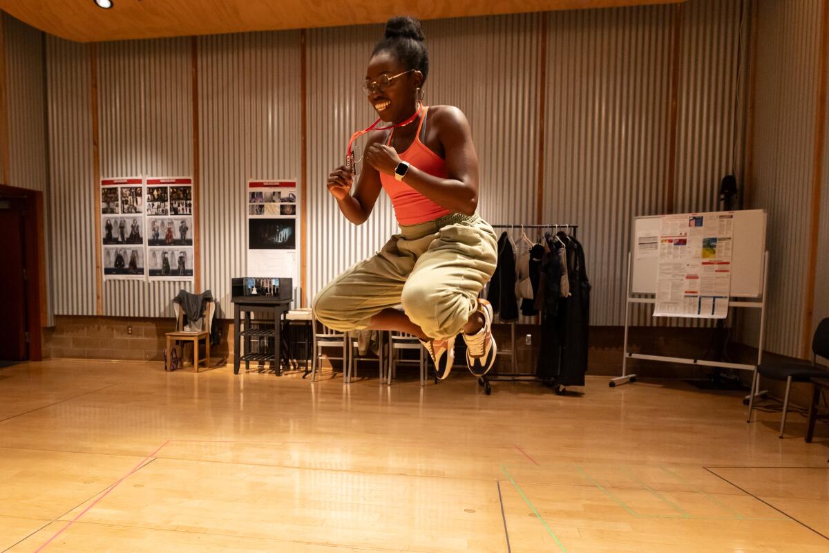 A woman mid-jump in a rehearsal room