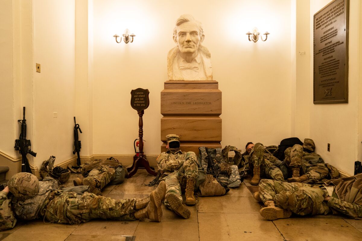 Guns are propped against the wall and Guardsmen are stretched out around a bust of Lincoln.