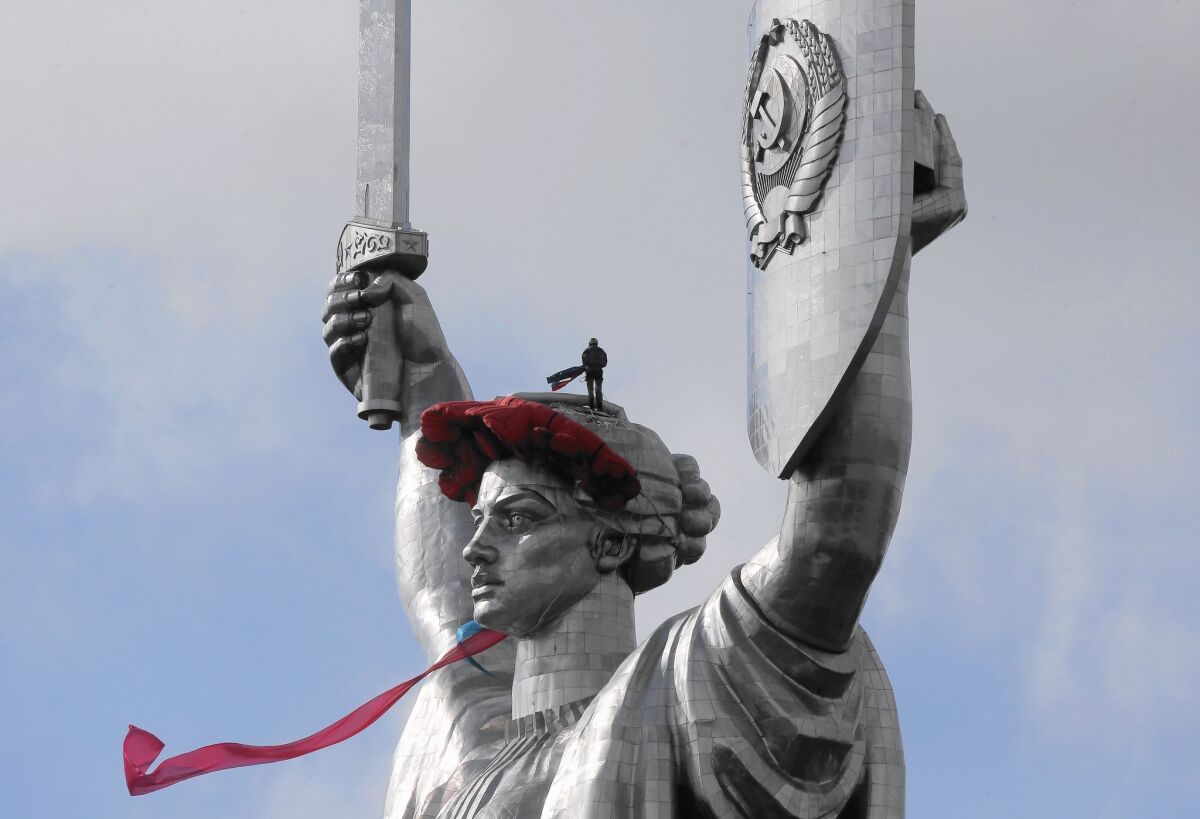 A worker installs a wreath of poppies and ribbon on the Mother Motherland monument in Kiev, Ukraine, on May 8 to mark the anniversary of the Nazis' World War II defeat. The statue may lose the Soviet seal on its shield.
