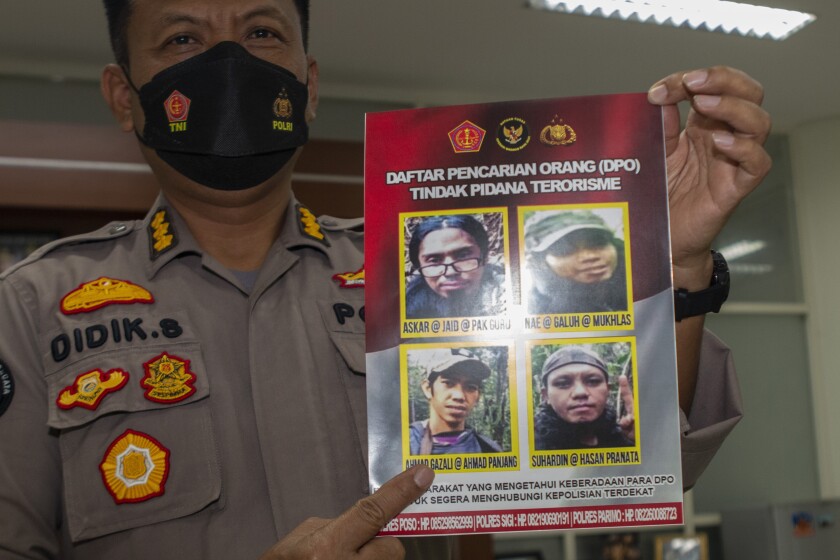 Central Sulawesi Regional Police spokesperson Col. Didik Supranoto shows a photo of Ahmad Gazali, bottom left, also known as Ahmad Panjang, that is displayed on a wanted poster along with other militant suspects, during a news conference in Palu, Indonesia, Tuesday, Jan. 4, 2022. Indonesian security forces killed suspected militant Gazali, accused of beheadings, in a shootout Tuesday in a sweeping counterterrorism campaign against extremists in remote mountain jungles, police said. (AP Photo/Mohammad Taufan)