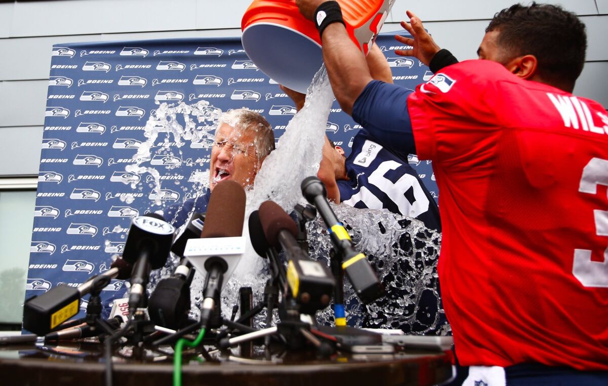 Pete Carroll gets it: The Seattle Seahawks coach gets doused by Russell Wilson, right, and Zach Miller as part of the ALS Ice Bucket Challenge.