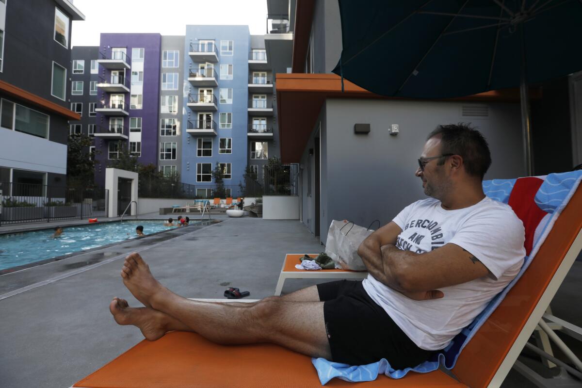 Mike Kaesermann, 38, relaxes as he watches his family play in the pool at an apartment building on Sixth Street, where they are renting a unit during their vacation.