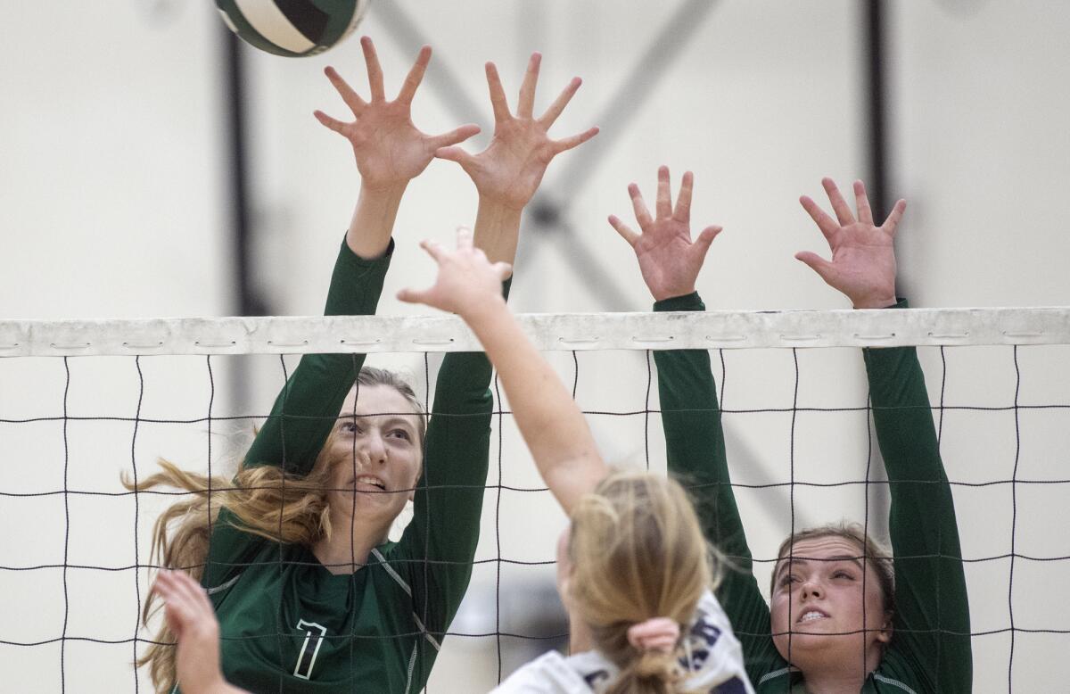 Costa Mesa's Lorelei Hobbis, left, and Frinny Ross, right, attempt to block a shot at the net by Calvary Chapel's Gabby Reinking in an Orange Coast League home match on Wednesday.