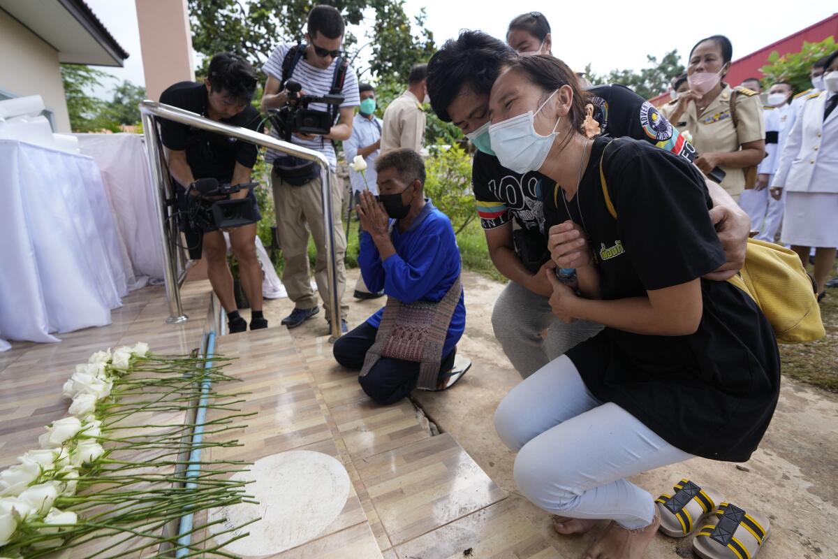 Relatives kneel, mourning those killed in an attack on a Thai day-care center