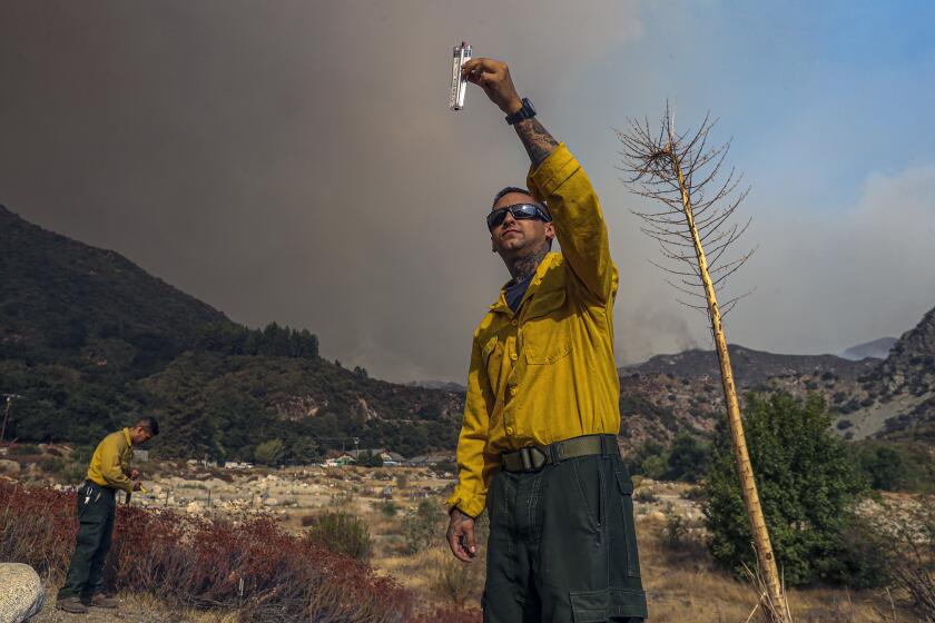 SAN GABRIEL MOUNTAIN, CA - SEPTEMBER 09: Angeles National Forest firefighters Jessy Alvarez, left, and Gabriel Ayers get weather readings as Bobcat fire rages above Rincon Fire Station along Highway 39 on Wednesday, Sept. 9, 2020 in San Gabriel Mountain, CA. (Irfan Khan / Los Angeles Times)