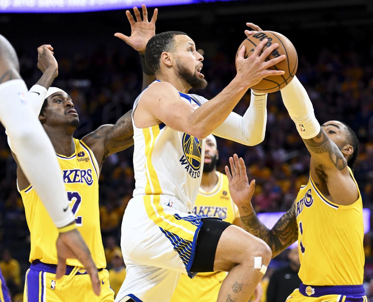 Warriors guard Stephen Curry, center, elevates for a layup against the Lakers during Game 5.