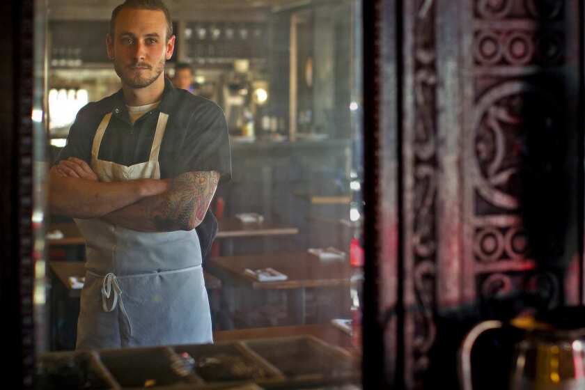 Chef Trevor Rocco, reflected in an old mirror from an antique kitchen cabinet, is the man behind the new restaurant's menu.