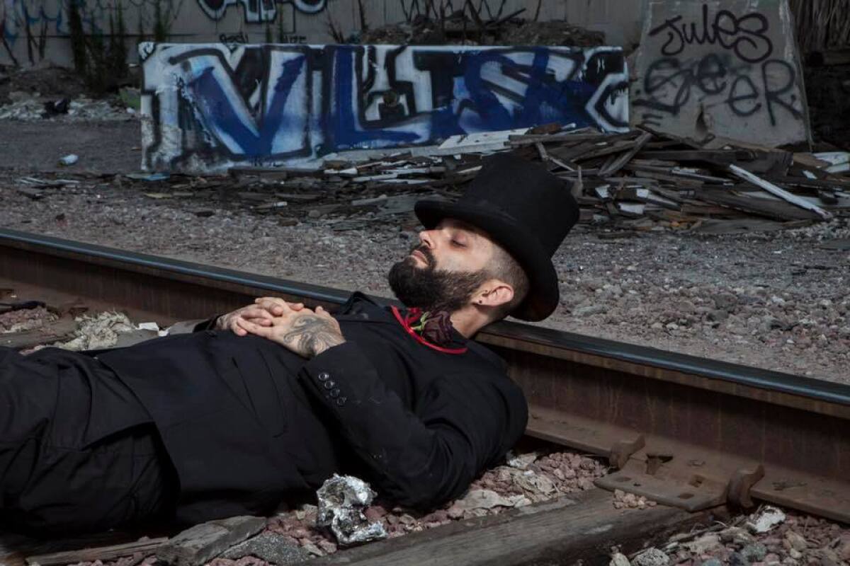 A figure reclines on a railroad track.