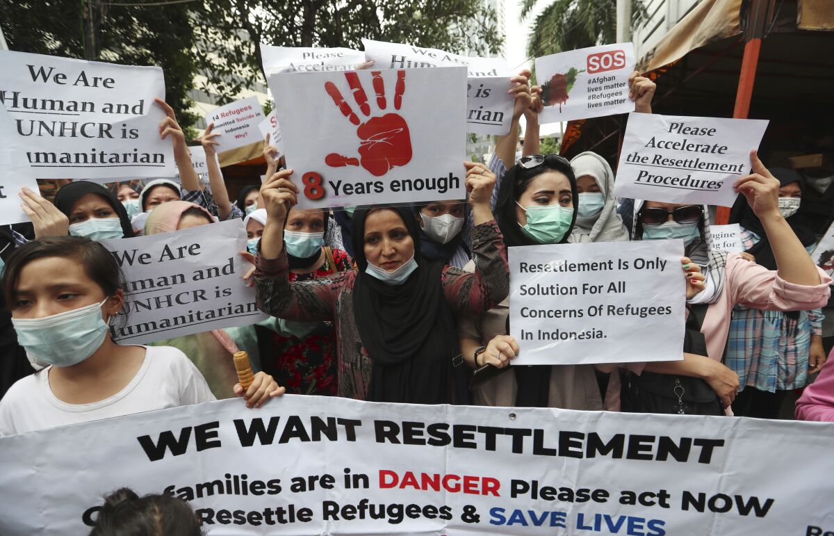 Afghan women and children refugees living in Indonesia hold posters during a rally outside a building that houses UNHCR representative office in Jakarta, Indonesia, Monday, Nov. 15, 2021. Hundreds of Afghan refugees and asylum seekers living in Indonesia rallied in front of the U.N. refugee agency office in Jakarta on Monday to urge it to speed up their resettlement.(AP Photo/Achmad Ibrahim)