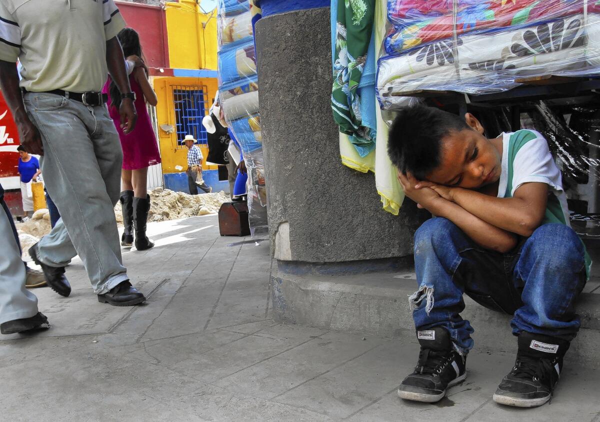 Anderson Daniel, 7, of San Pedro Sula, Honduras, sits exhausted on a hot street in Tapachula, Mexico. He stays at a shelter for migrant children in the city.