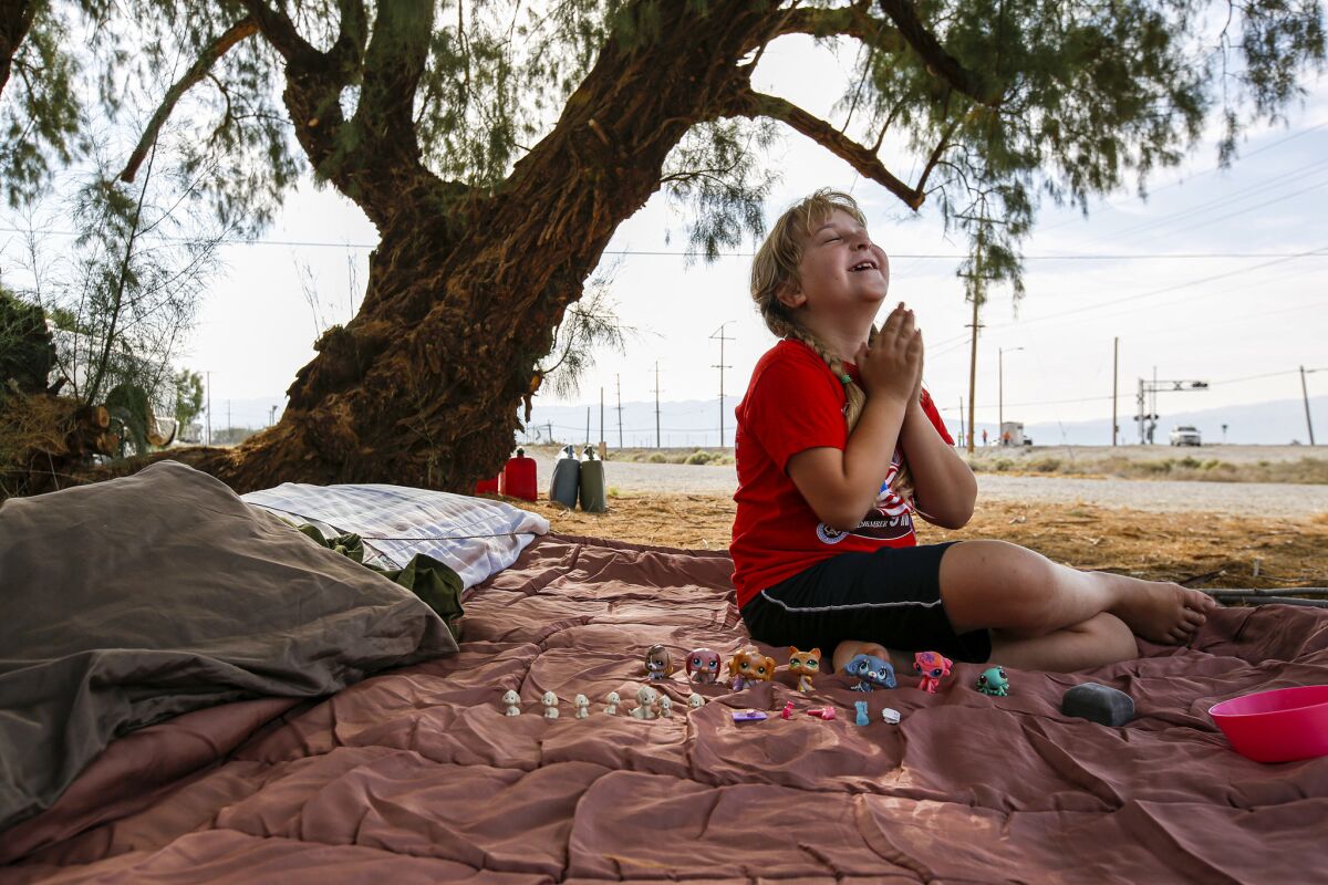 Brooke Thompson, 8, plays on the sleeping bag that her family slept in after a pair of major earthquakes drove them out of their home in Trona. (Irfan Khan / Los Angeles Times)