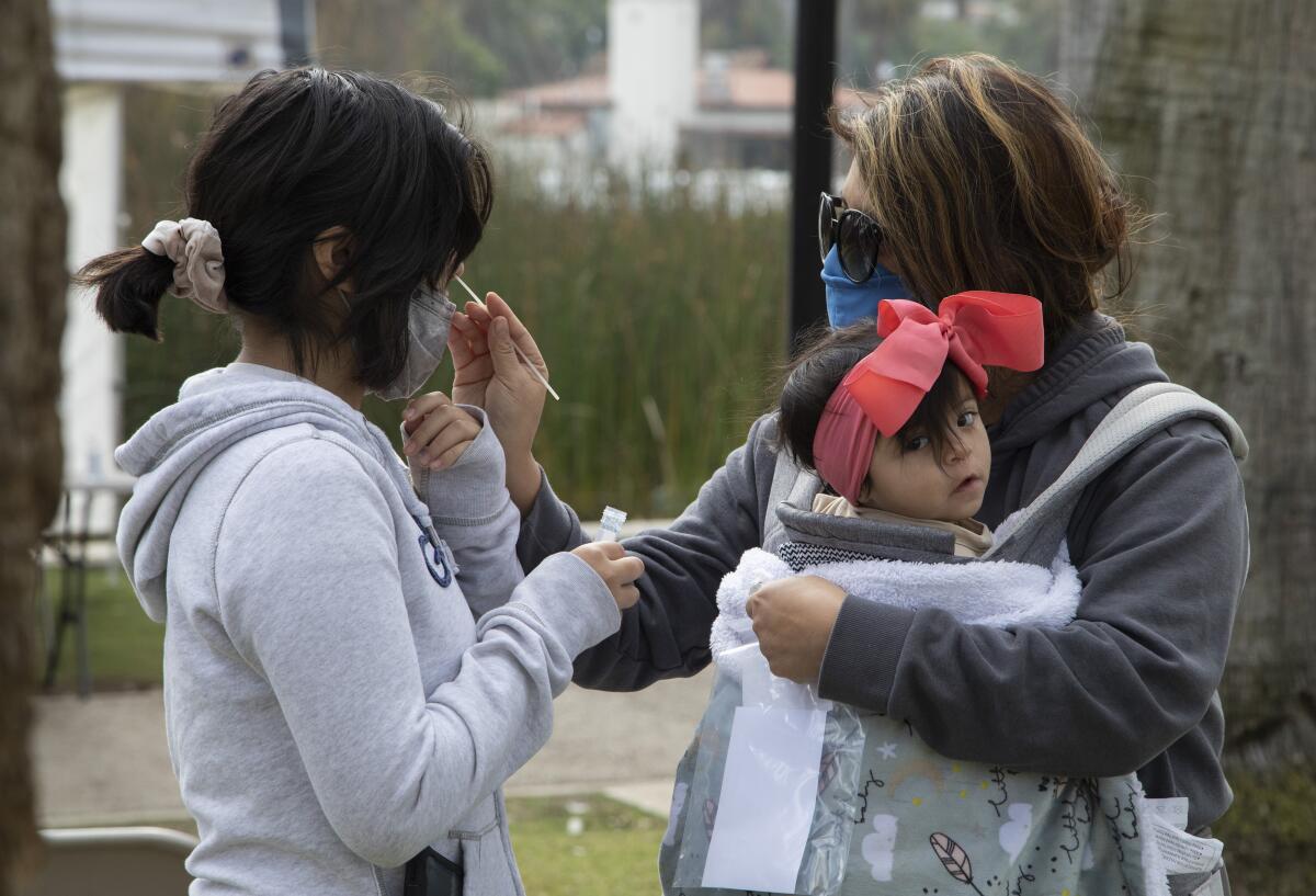 A woman swabs her daughter for a coronavirus test.