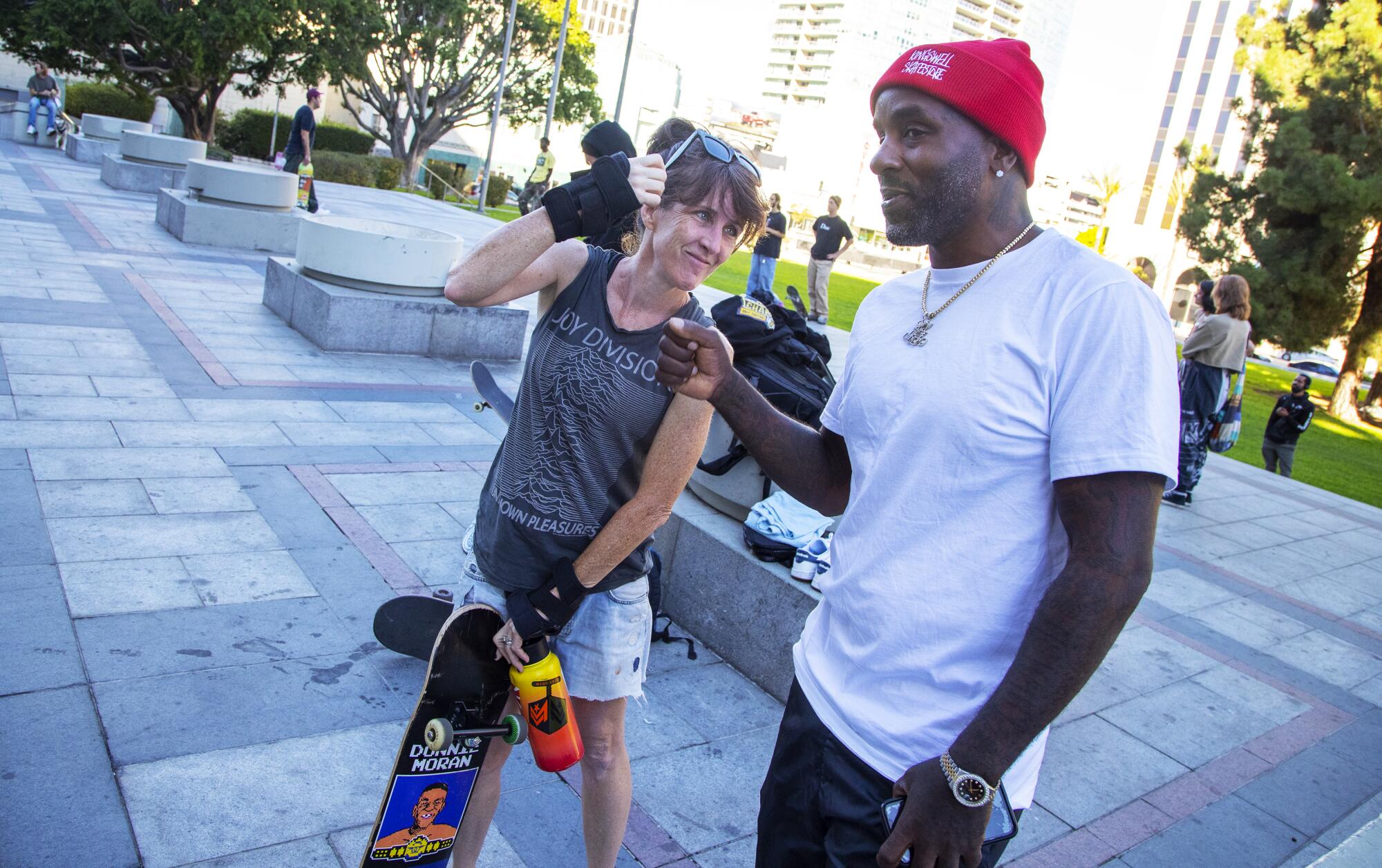 Skateboarder Heather McAdams greets Don Cooley, right, unofficial host at JKwon Plaza in Koreatown.