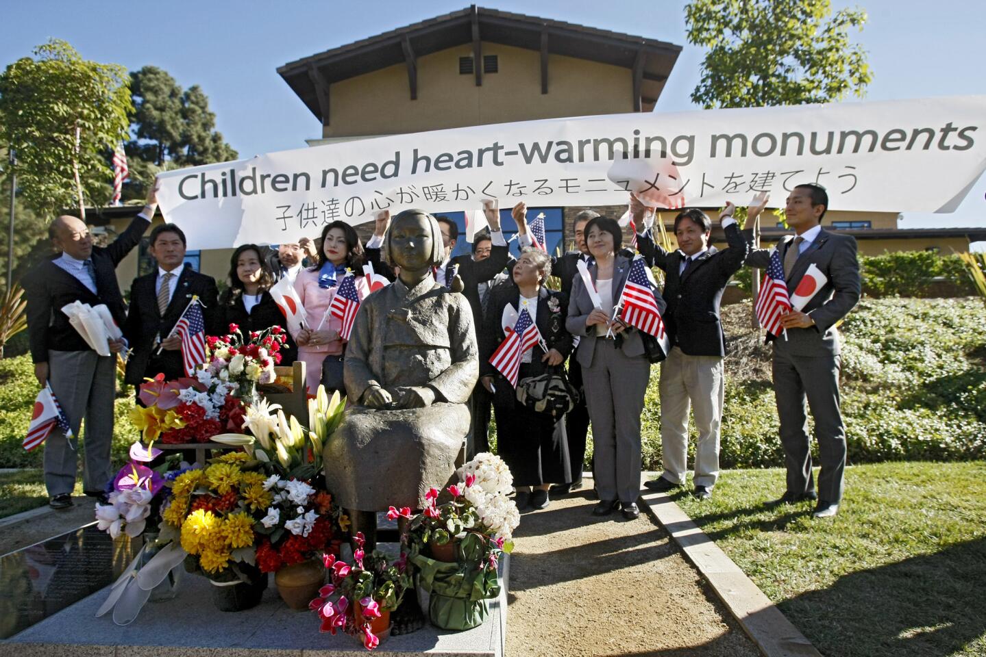 A delegation of Japanese city council members brought a sign that says "Children need heart-warming monuments" to the Comfort Women statue at Central Park in Glendale on Thursday, January 16, 2014. The delegation first delivered a letter to the Glendale city clerk asking this statue be removed because they do not approve of its message.