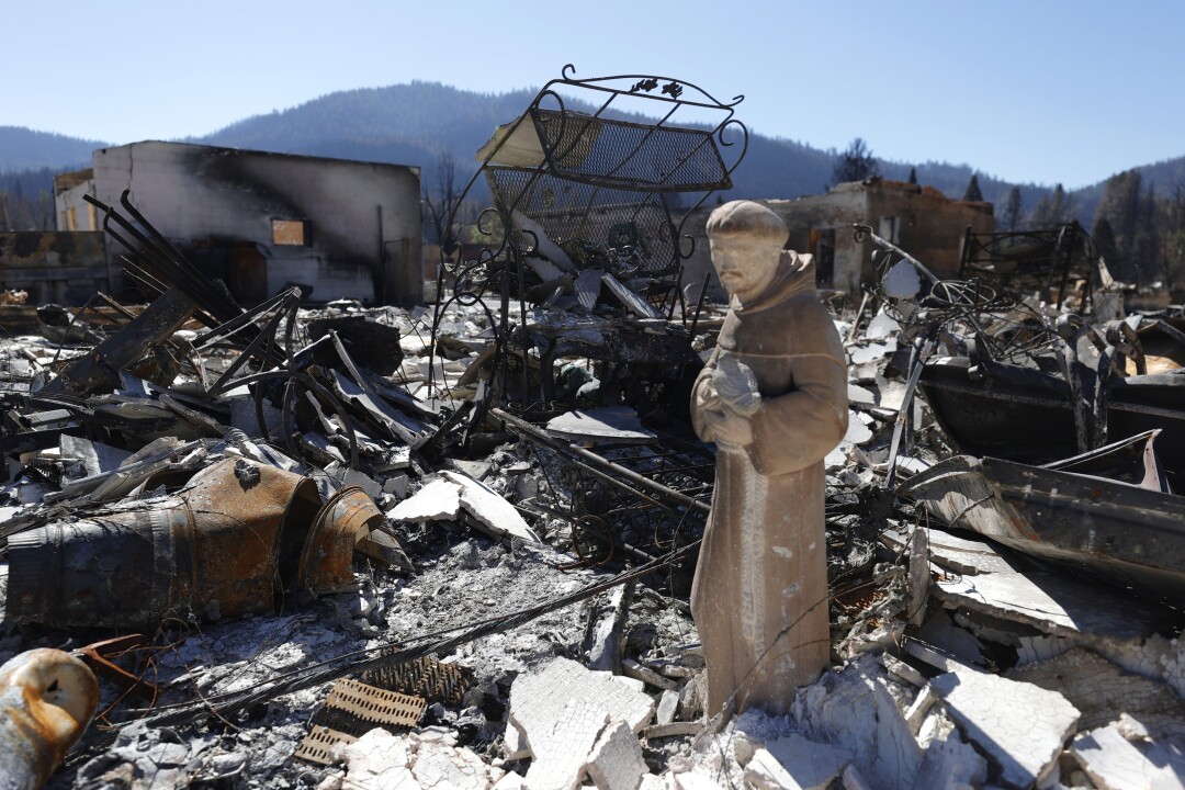 A religious statue stands amid rubble