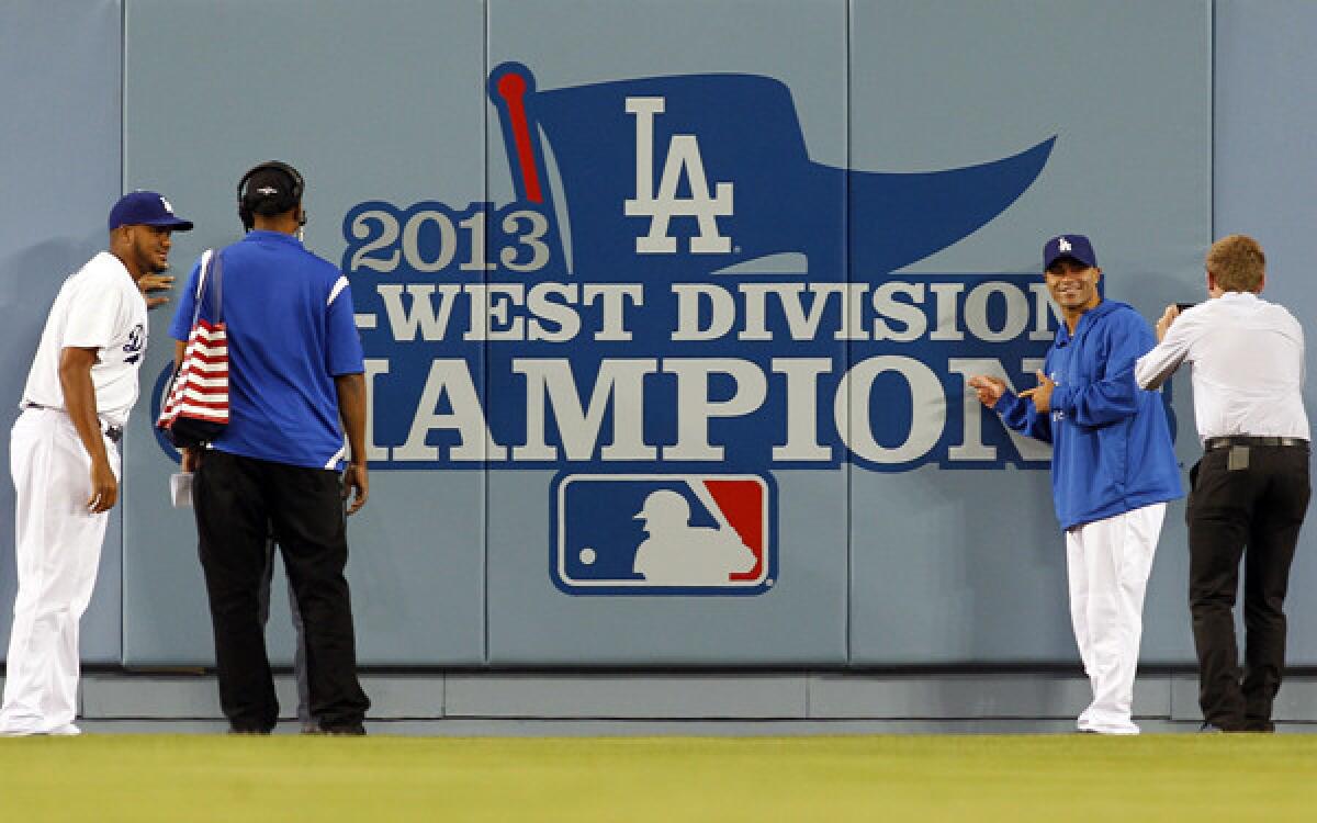 Dodgers pitcher Kenley Jansen, left, and utility player Jerry Hairston at the Dodgers' 2013 NL West Division championship banner before their game against the Colorado Rockies on Friday night.