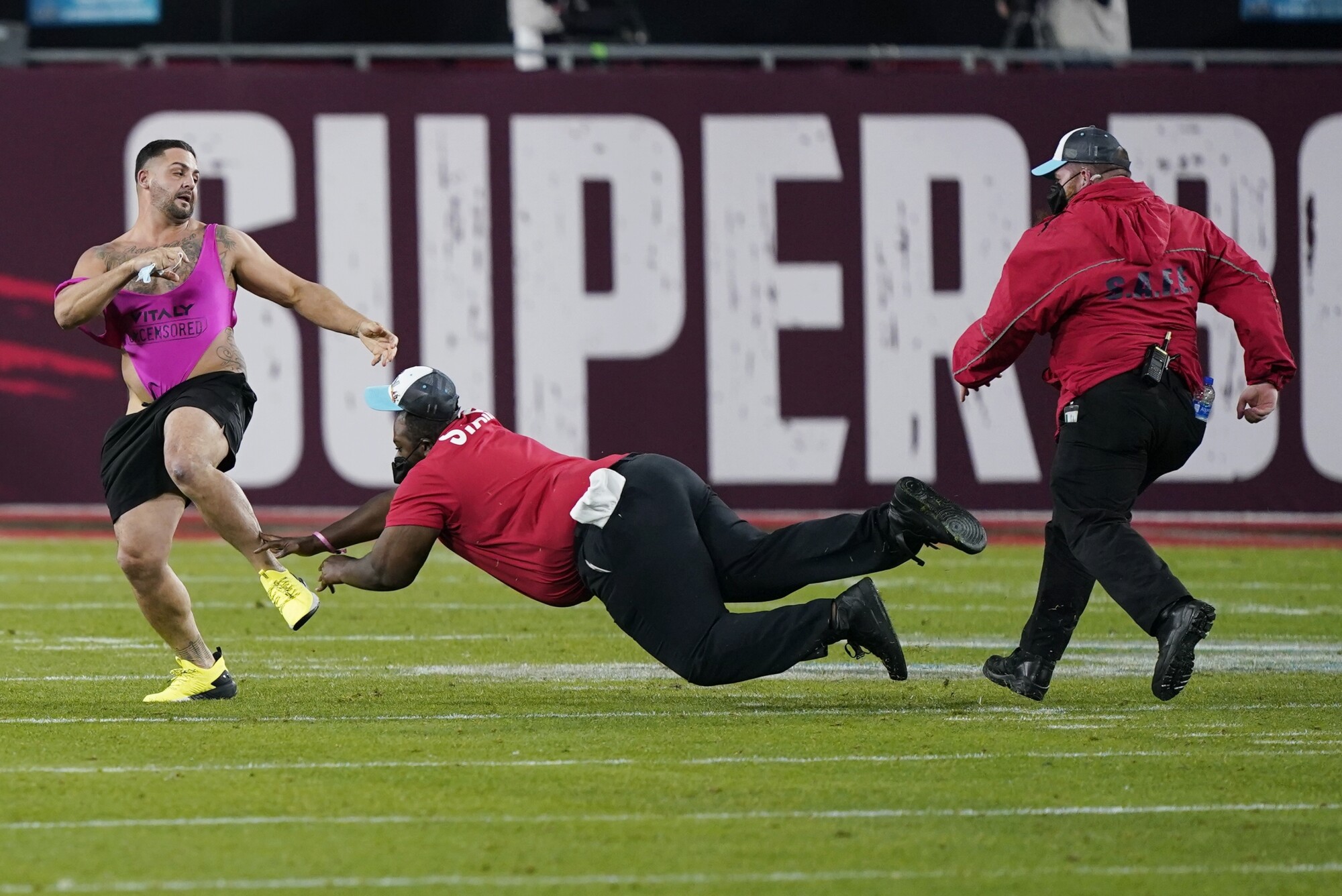 Security tries to grab a fan on the field during Super Bowl LV.