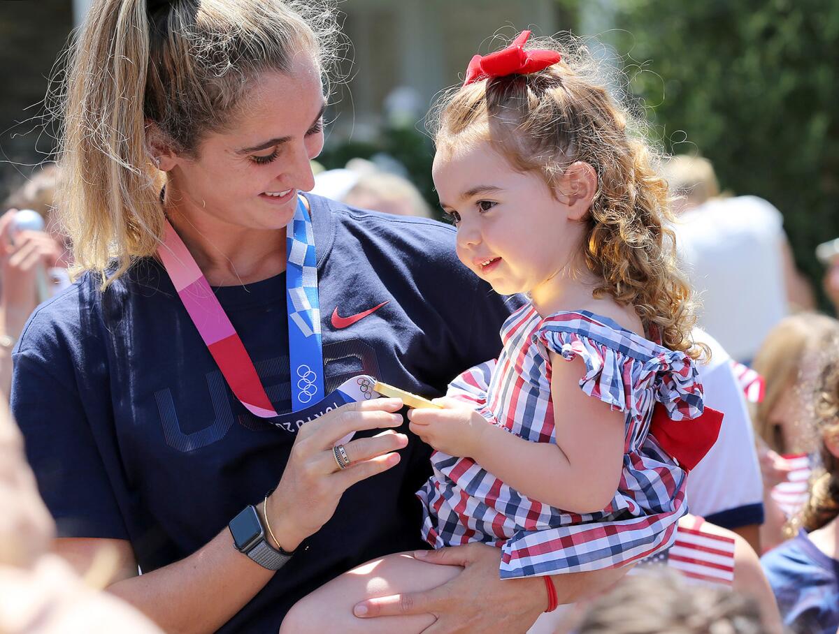 Maddie Musselman shows off her gold medal that reflects on the face of a neighborhood youngster during her party Monday.