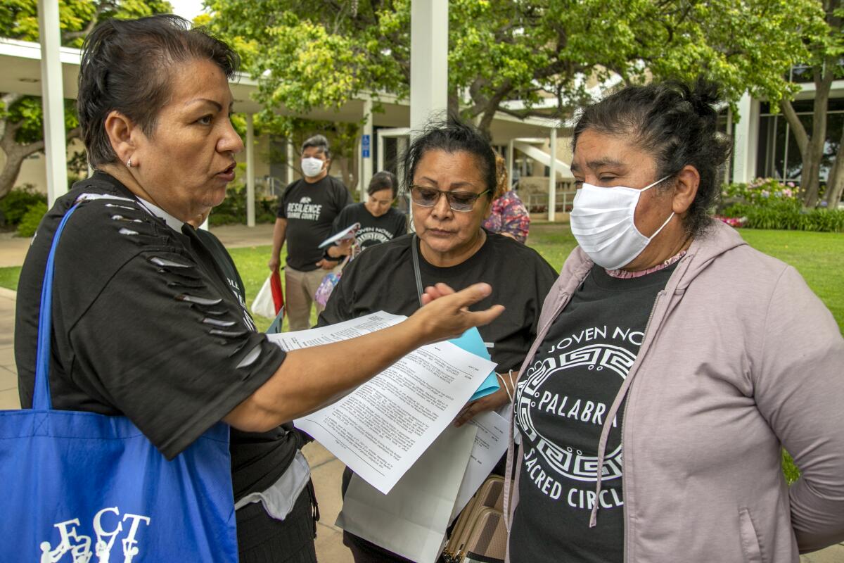 Costa Mesa resident Juanita Trejo, left, explains the City Council's meeting agenda to demonstrators.