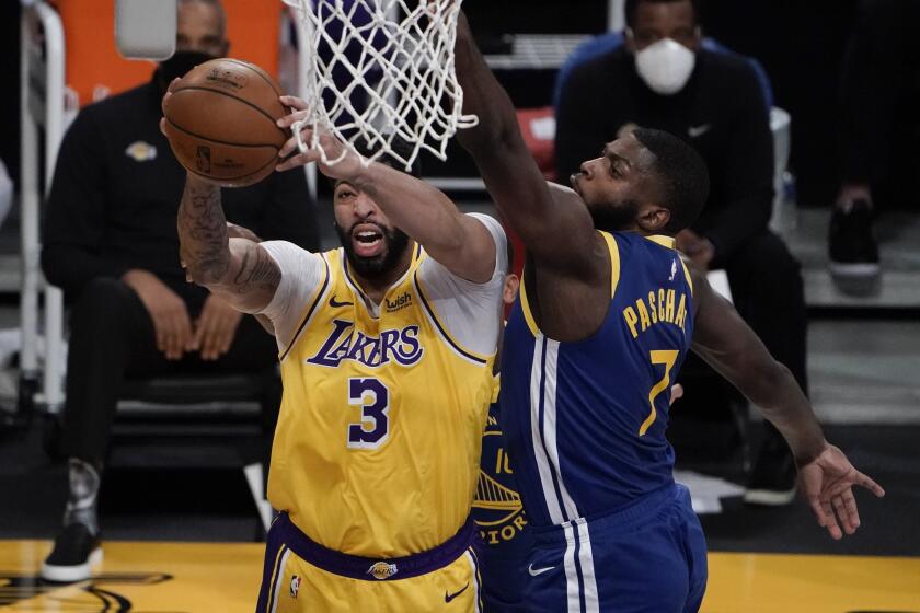 Los Angeles Lakers' Anthony Davis, left, grabs a rebound against Golden State Warriors' Eric Paschall during the first half of an NBA basketball game, Monday, Jan. 18, 2021, in Los Angeles. (AP Photo/Jae C. Hong)